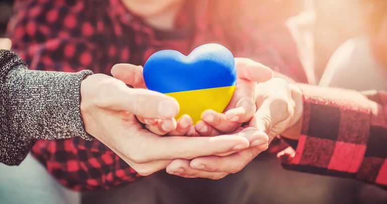 rodzina trzymająca w ręku serce w barwach ukraińskich niebiesko-żółtych